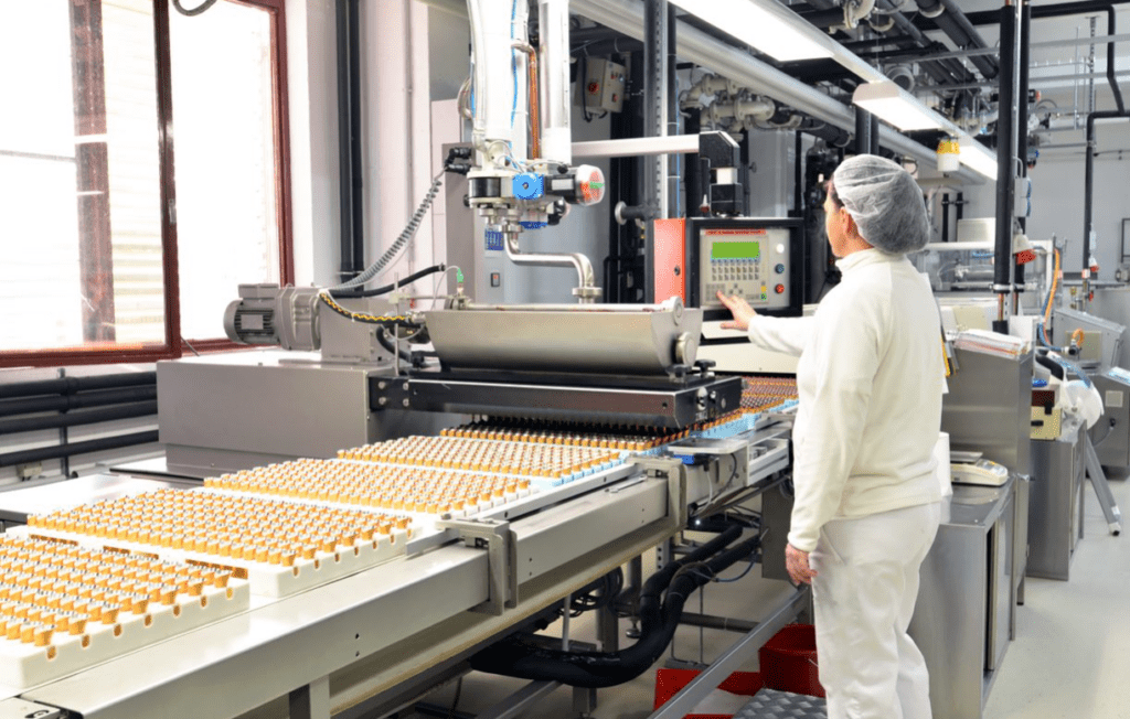 Worker at conveyor belt in food factory.