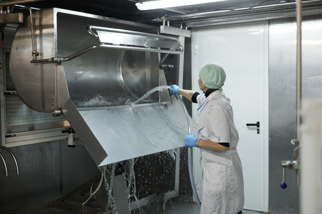 Working cleaning dairy curdling equipment with water.