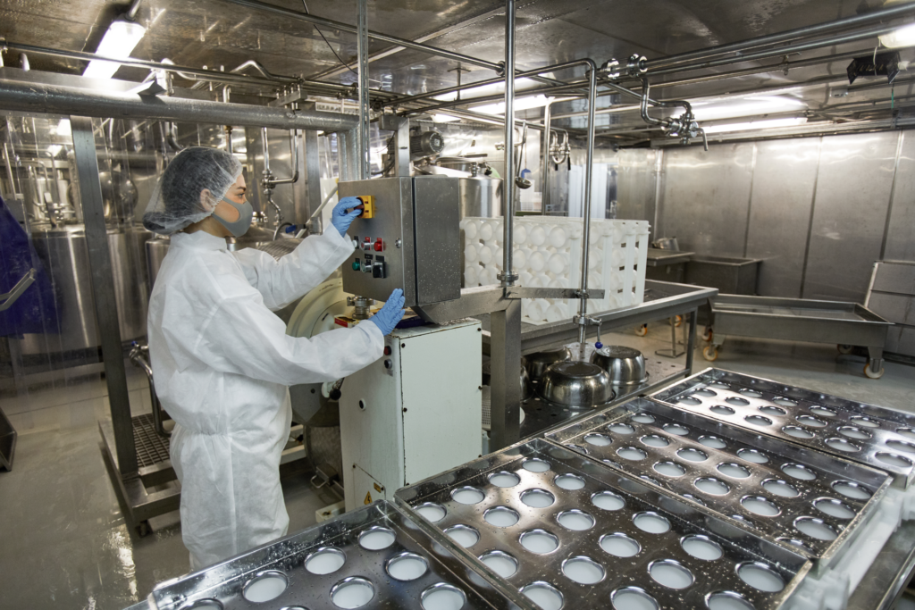 Worker in dairy plant at assembly line.