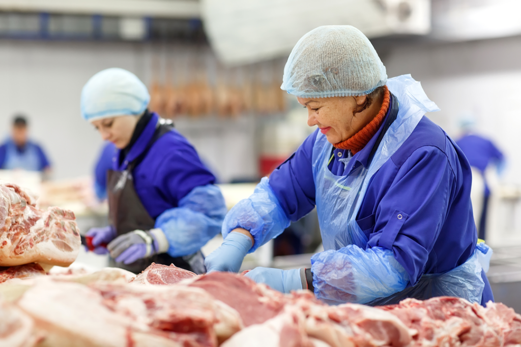 Worker cutting meat in a slaughterhouse.