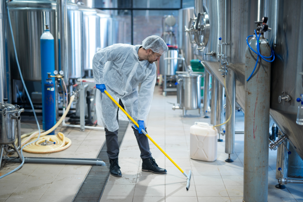 Worker in food processing plant washing the floor.