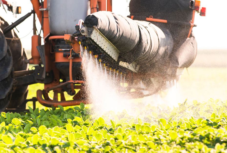 Tractor spraying pesticides on a soy field 
