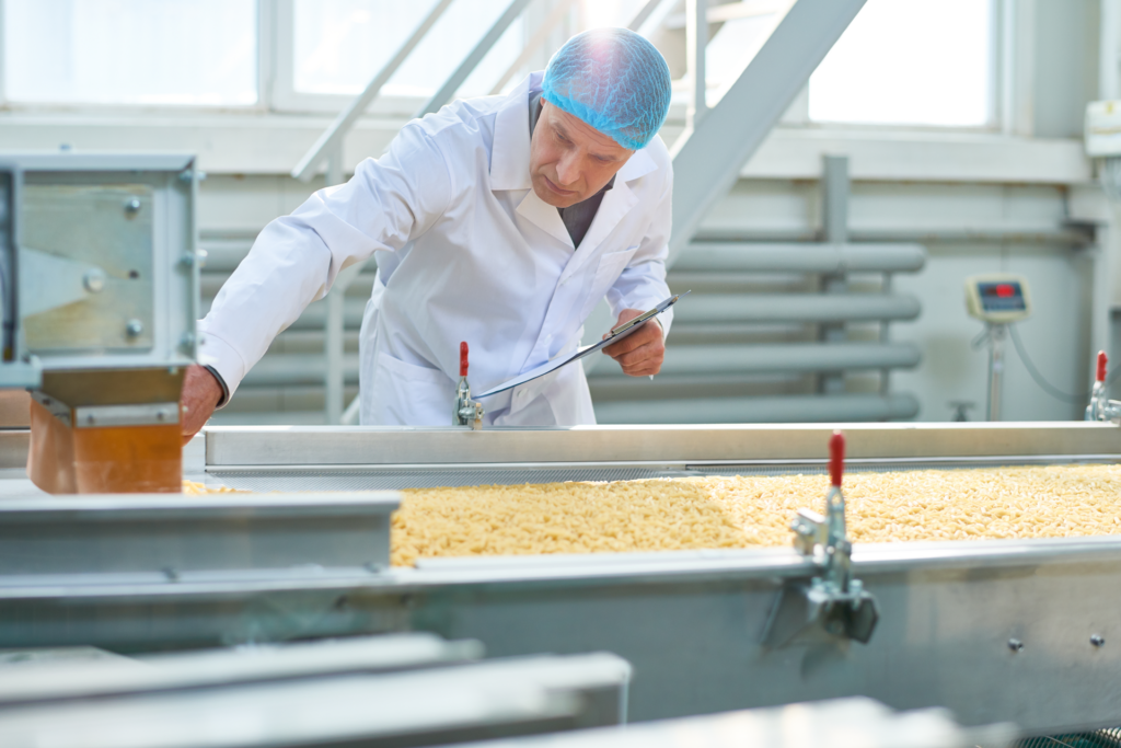 Food processing worker examining food products moving down a conveyor line. 