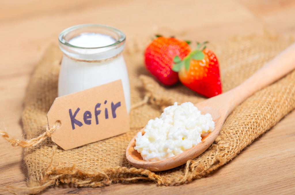 Container of kefir with wooden spoon and strawberries. 