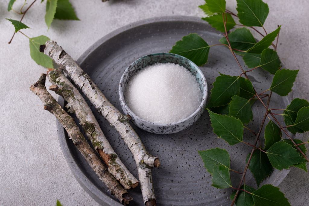 Sugar substitute in a bowl surrounded by birch sticks and leaves.