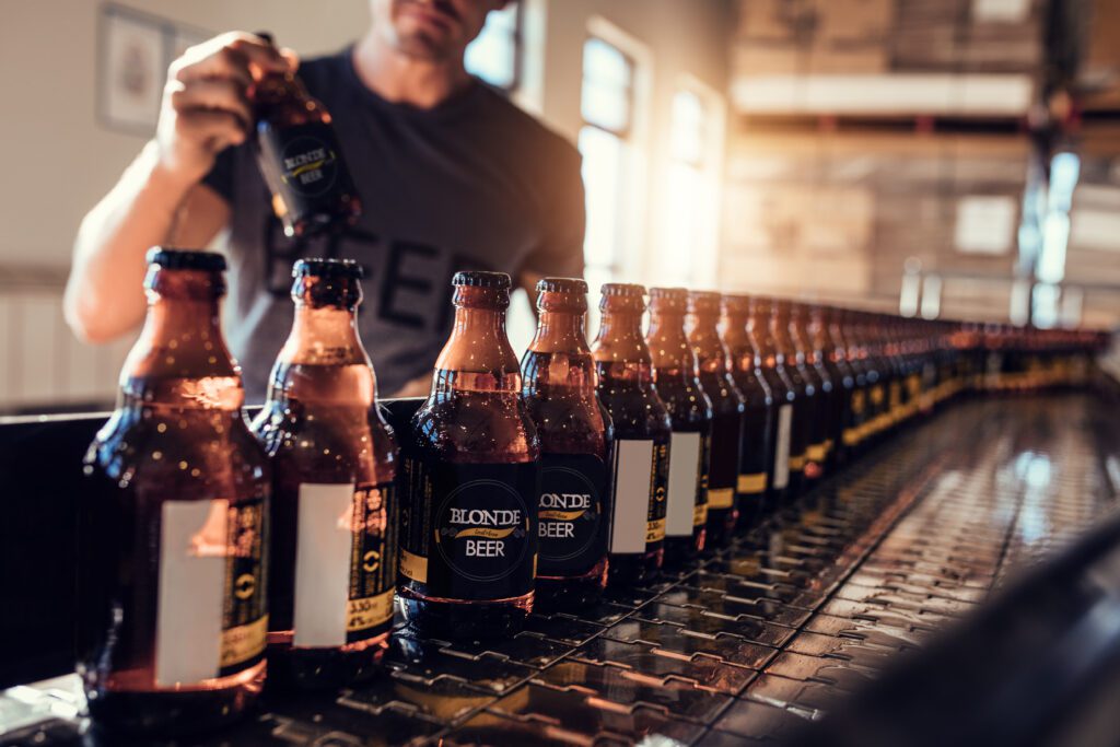Production worker verifying correct labels on bottles in a bottling plant.