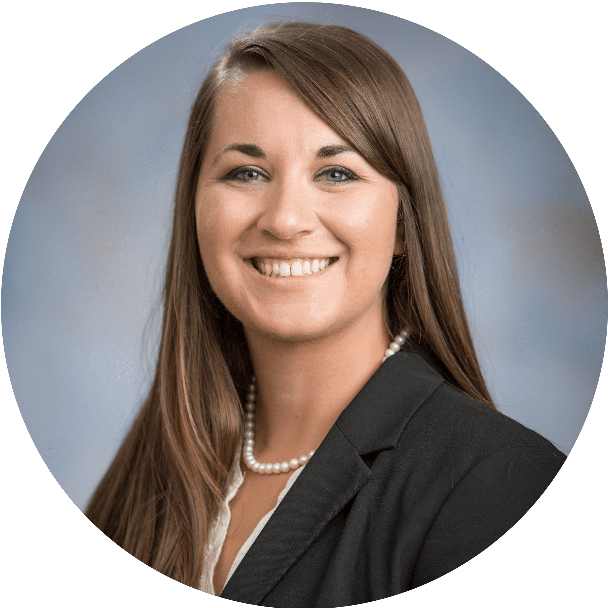 Smiling woman in a black blazer with a pearl necklace, facing the camera.