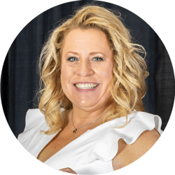 Portrait of a smiling blonde woman in a white blouse against a dark backdrop, head and shoulders. 2019